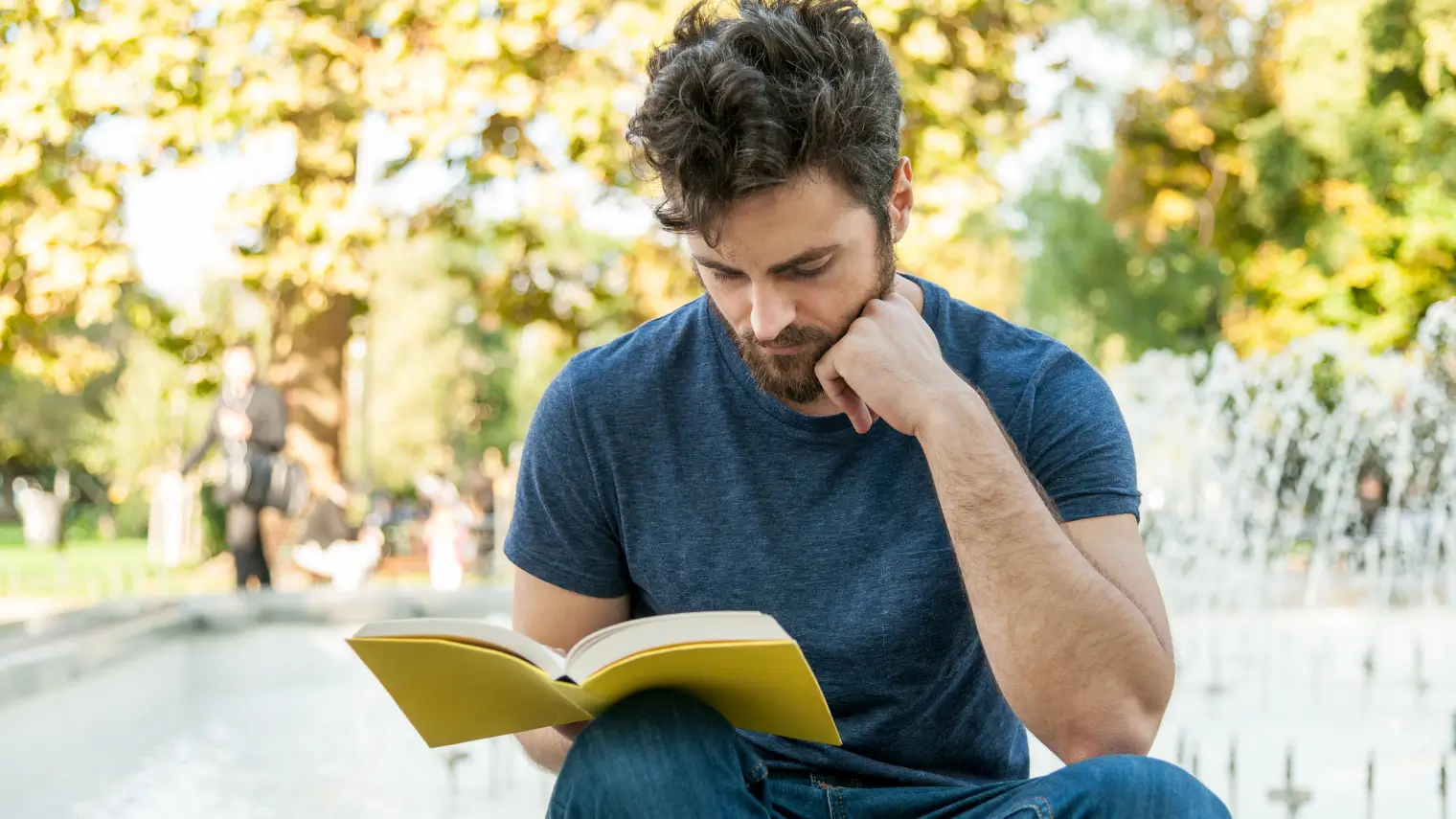 Man reading a book outdoors.
