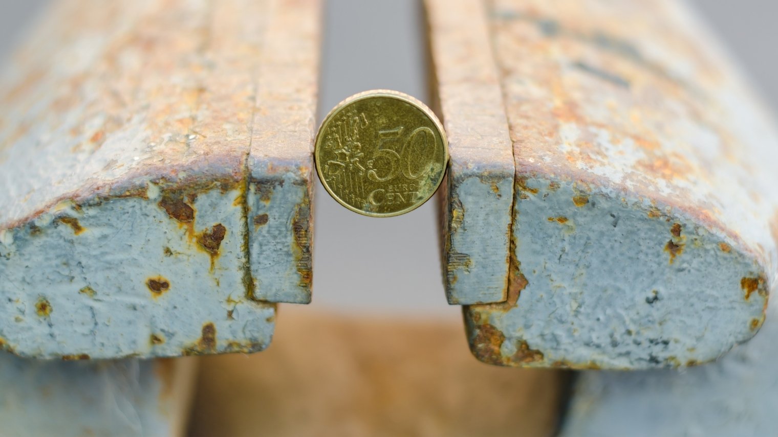 50-cent coin squeezed between two benches, illustrating a poker squeeze play.